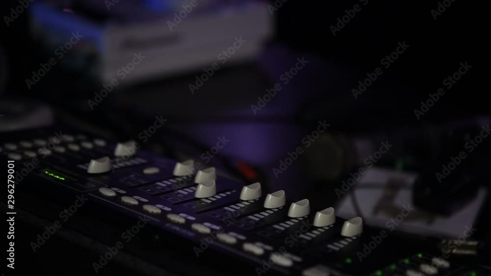 A DJ microphone and a mixing console lie on a table in a nightclub. A DJ microphone and a mixing console lie on a table in a nightclub.