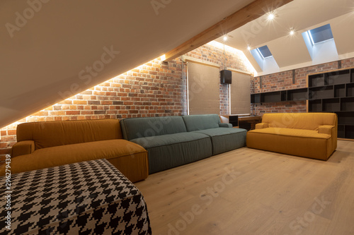 Fotografie Soft couch and empty bookcase located inside spacious living room with brick wal