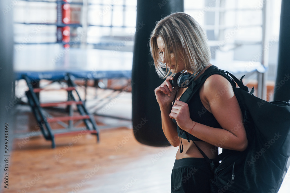 Fototapeta premium On the way to the gym. Adult female with black bag and headphones
