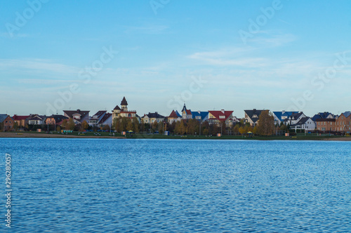 A lake with blue water and sky. Beautiful houses and cottages on the horizon.