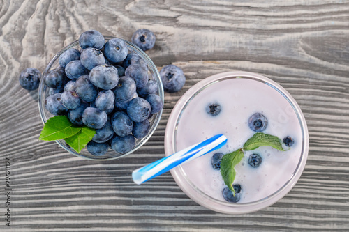 Berry smoothie or yogurt in glass and blueberries in bowl on wooden table