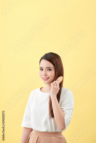 Portrait of beautiful young woman combing her hair and smiling © makistock