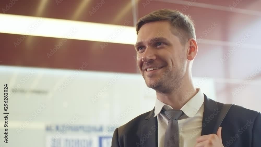 Medium shot of friendly young businessman talking to unrecognizable colleague or business partner and smiling Medium shot of friendly young businessman talking to unrecognizable colleague or business partner and smiling