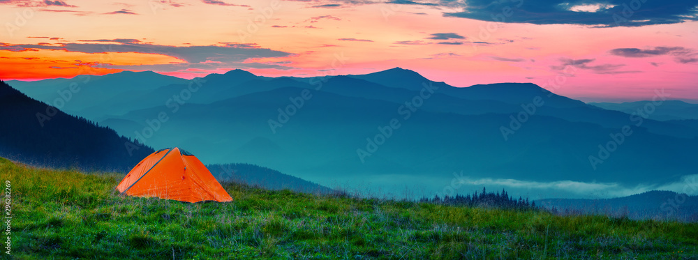 Orange tent in mountains at sunset