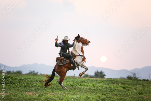 Mon riding horse against sunset with holding gun
