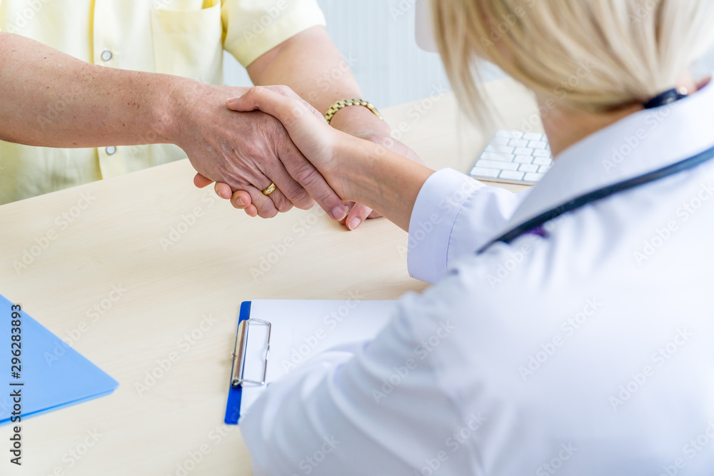 Female doctor shaking hand with the elderly male patient. Female doctor shaking hand with the elderly male patient.