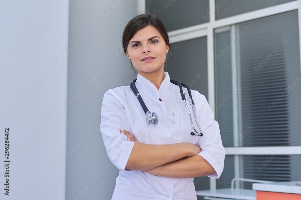 Portrait of confident young female medic with stethoscope with folded hands Portrait of confident young female medic with stethoscope with folded hands