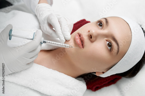Hands of cosmetologist making lips injection.