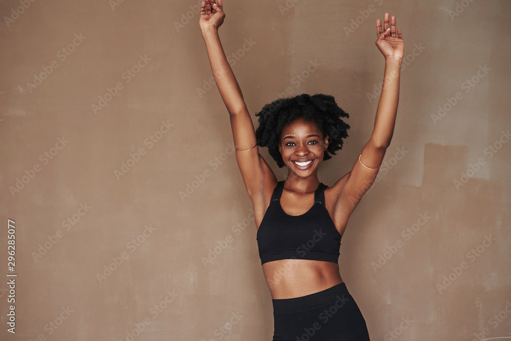 Fototapeta premium Feels great. Young beautiful afro american woman in the studio against brown background