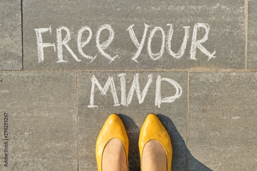 Fotografie Free your mind text on gray sidewalk with woman legs, top view