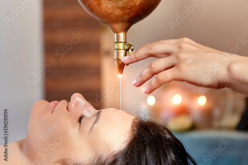 ayurveda massage alternative healing therapy.beautiful caucasian female getting shirodhara treatment lying on a wooden table in India salon. photo