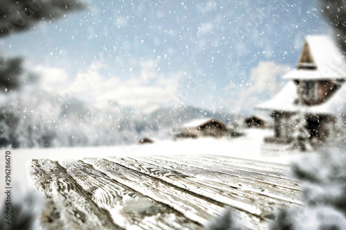 Wooden table top with blurred snowy winter background.