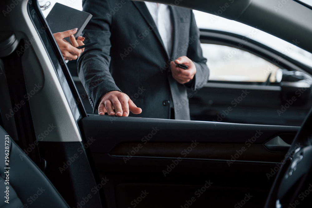 Photo from the inside of vehicle. Female customer and modern stylish bearded businessman in the automobile saloon Photo from the inside of vehicle. Female customer and modern stylish bearded businessman in the automobile saloon