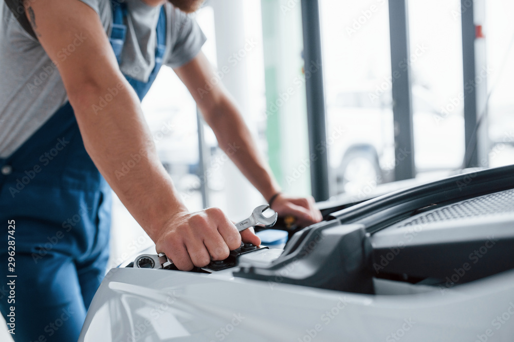 Have a job at daytime. Process of repairing car after accident. Man working with engine under the hood Have a job at daytime. Process of repairing car after accident. Man working with engine under the hood