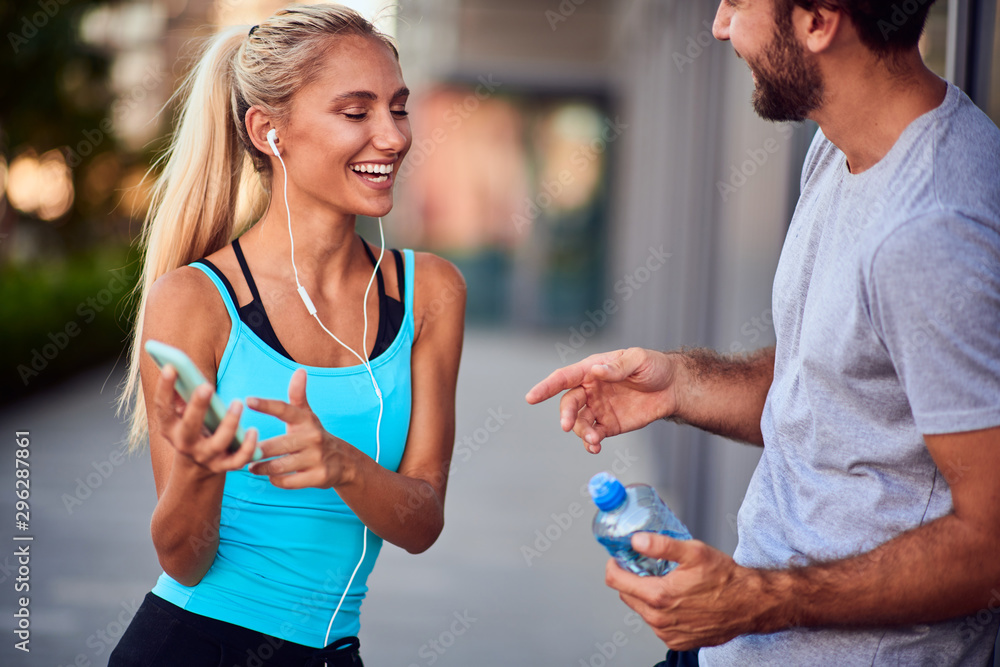 Modern woman and man jogging / exercising in urban surroundings and using cellphone at a pause / break. Modern woman and man jogging / exercising in urban surroundings and using cellphone at a pause / break.