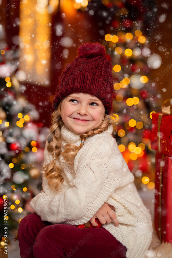 happy cheerful girl in a hat and with pigtails on the veranda of the house in anticipation of Christmas happy cheerful girl in a hat and with pigtails on the veranda of the house in anticipation of Christmas