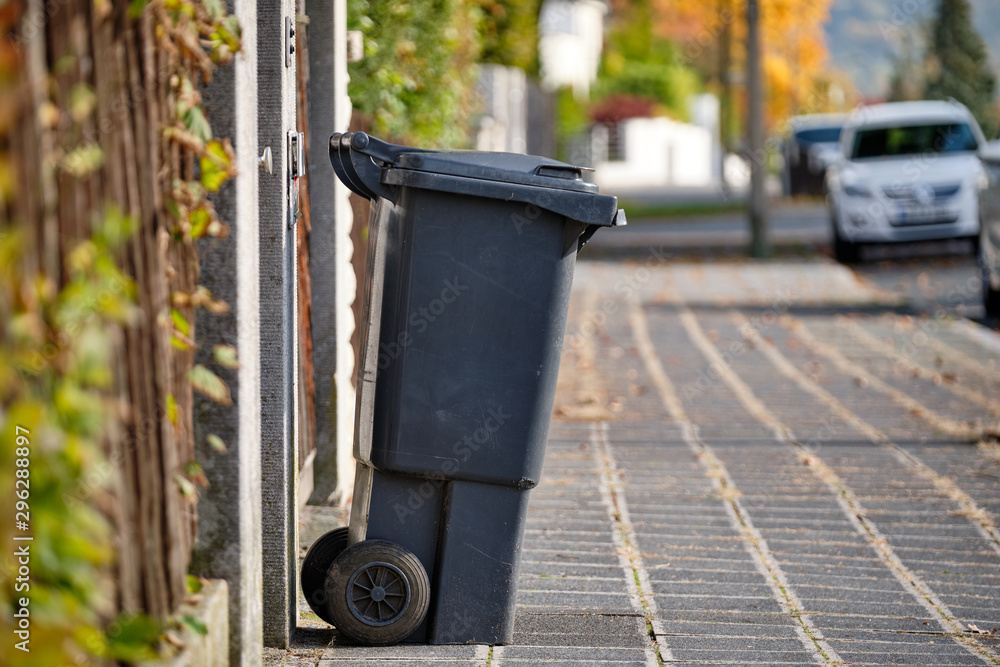 Black garbage bin for residual waste standing on the pavement in a residential area on a sunny autumn day in Germany Black garbage bin for residual waste standing on the pavement in a residential area on a sunny autumn day in Germany