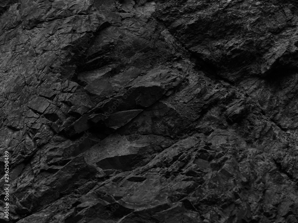 Black stone background. Rocks texture. Bright black grunge background. Mountain close-up. Black and white background. Volumetric rocky background.