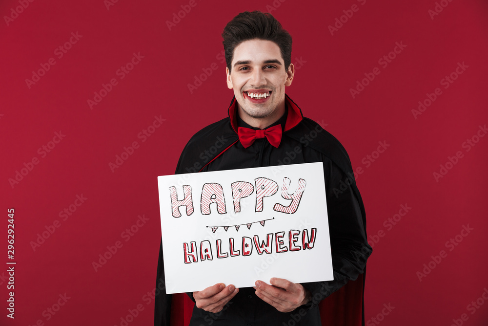 Image of vampire man in black costume holding halloween paper board Image of vampire man in black costume holding halloween paper board