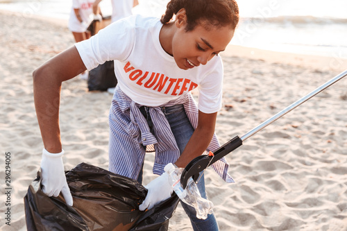 Tableau sur toile Image of joyful volunteers cleaning beach from plastic with trash bags