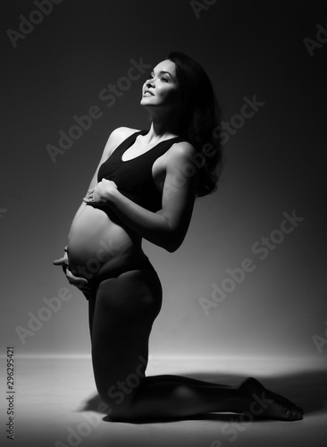 Pregnant woman in a black bathing suit on a gray background. © oshepkov