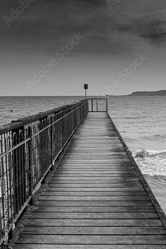 Moody black and white seascape and a jetty.