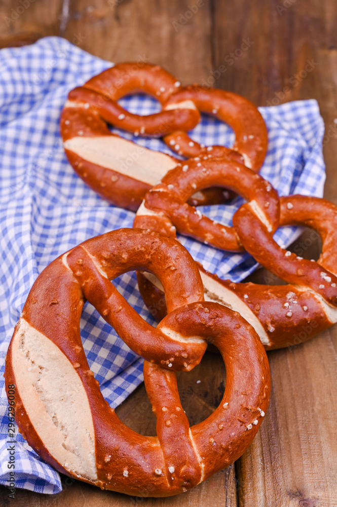 Bavarian pretzel decorated with a blue and white cloth on a rustic wooden board - Munich Oktoberfest. Vertical format. Background and free space for text. Traditional pastries for the festival. Bavarian pretzel decorated with a blue and white cloth on a rustic wooden board - Munich Oktoberfest. Vertical format. Background and free space for text. Traditional pastries for the festival.