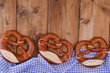 Bavarian pretzel decorated with a blue and white cloth on a rustic wooden board - Munich Oktoberfest. Horizontal format. Background and free space for text. Traditional pastries for the festival.