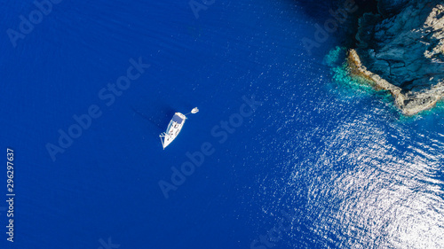 Sailboat while cruising, sailing at opened sea. Island with Lighthouse in beautiful deep blue sea. View from above, stunning aerial view, drone background.
