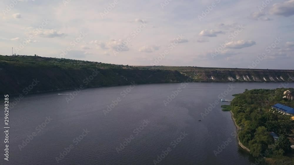 along the riverbank 4K aerial view, Drone flight along the riverbank moving near the trees.