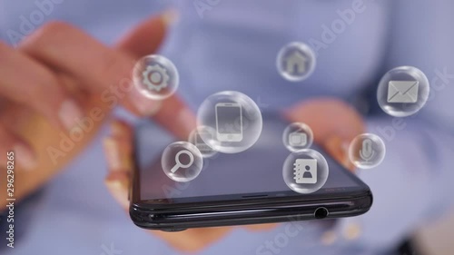 Woman hand touch smartphone screen, various application icons pop up, revolve floating around as a futuristic virtual interface. Connect to the future and the world through cloud services concept.