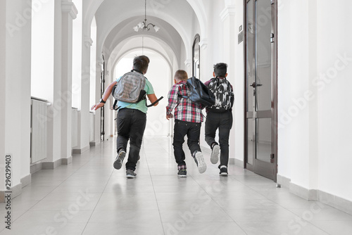 Group of schoolboys with school backpacks running.