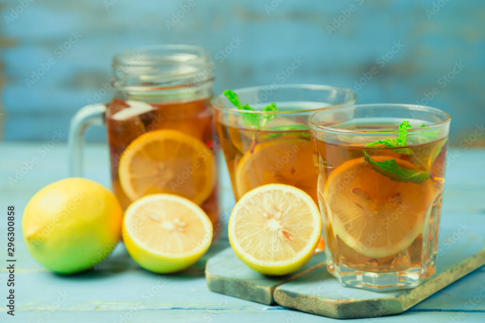 Iced tea with lemon slices and mint on wood background Iced tea with lemon slices and mint on wood background