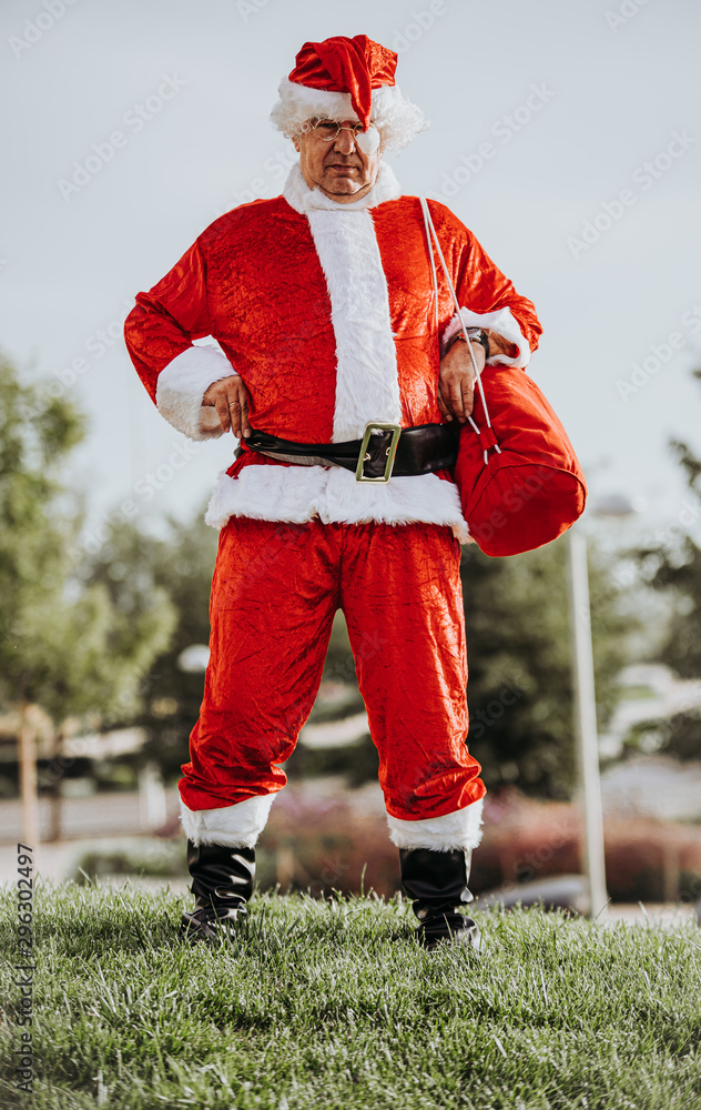 Obraz premium Stock photo of Vertical photo of papa noel without beard with arms resting on the body and yawning. Christmas time