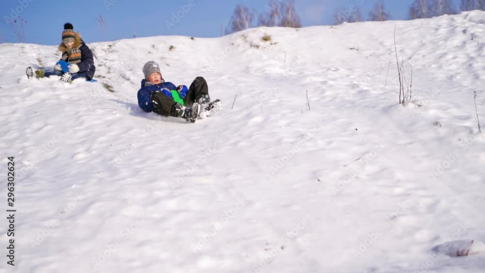 Frost winter season. Two children ride down a hill, winter games and fun. Kids laughing, sledging down a hill. Children ride down a hill, winter games and fun. Slow motion. Frost winter season. Two children ride down a hill, winter games and fun. Kids laughing, sledging down a hill. Children ride down a hill, winter games and fun. Slow motion.