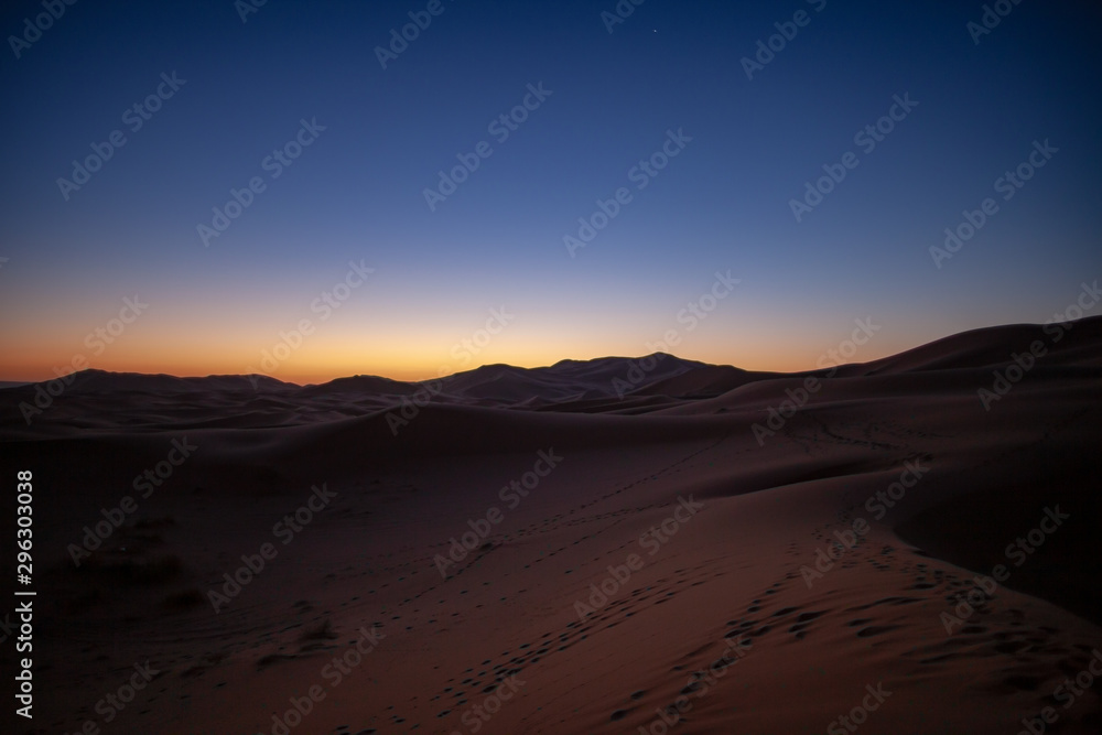 Erg Chebbi, Morocco, sand dunes of Sahara desert formed by wind are awakening in the first rays of the day, illuminated by the sun.