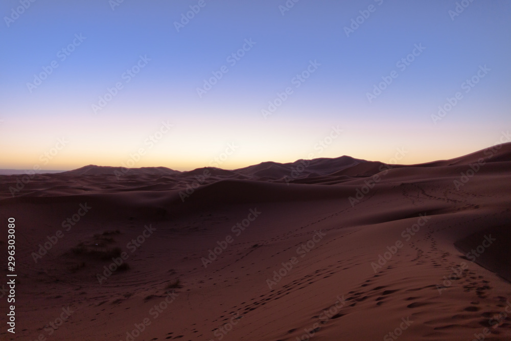 Erg Chebbi, Morocco, sand dunes of Sahara desert formed by wind are awakening in the first rays of the day, illuminated by the sun.