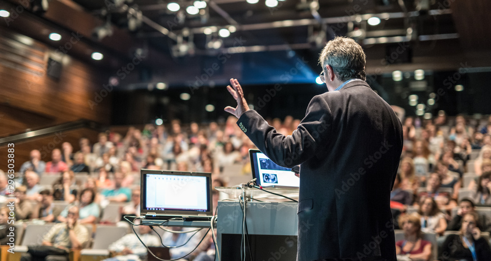 Fototapeta premium Speaker giving a talk on corporate business conference. Unrecognizable people in audience at conference hall. Business and Entrepreneurship event.