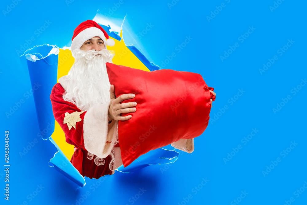 Santa Claus in a hole in the wall shows a bag with gifts Santa Claus in a hole in the wall shows a bag with gifts