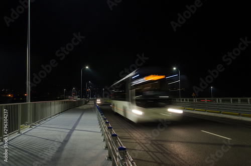 ON THE ROAD AT NIGHT - A bus on the bridge under the lights of street lamps