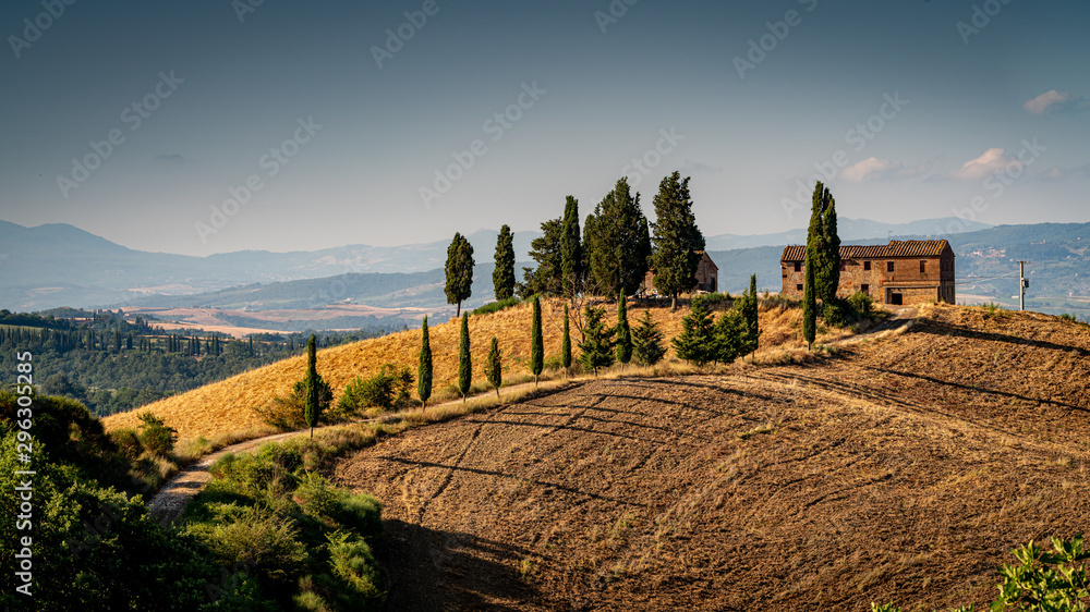 Typical Tuscany house on a hill with cypress trees and curved road