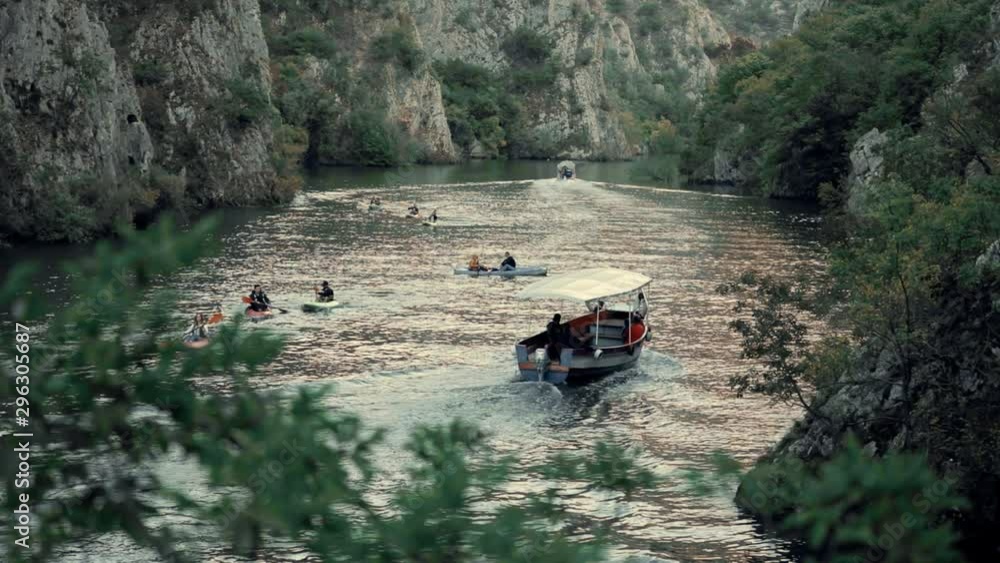 Sightseeing boat sailing on a canyon lake with people on kayaks in