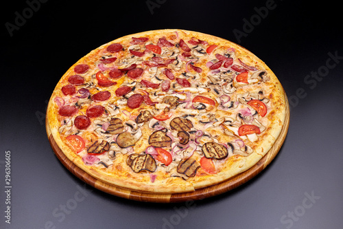 Pizza "Four Seasons" on wooden board on black concrete