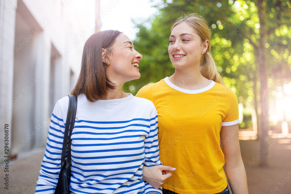 Obraz premium happy smiling mother and daughter walking outside together