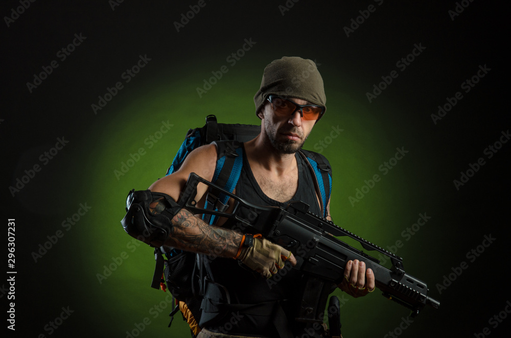 a man with a gun and a backpack on a dark background with emotions looking, aiming, watching, sneaking a man with a gun and a backpack on a dark background with emotions looking, aiming, watching, sneaking