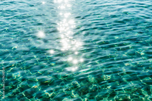Transparent turquoise surface of sea water with sun glare. Background, space for text.