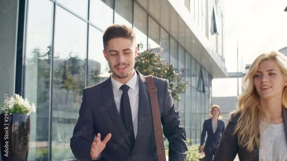 Front view medium shot of two young businesspeople, man and woman, having conversation while walking to work together Front view medium shot of two young businesspeople, man and woman, having conversation while walking to work together