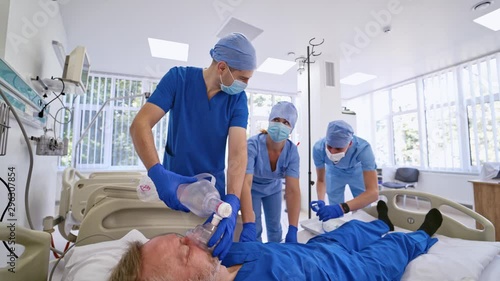 Doctors putting an oxygen mask on patient in hospital. First aid help. Reanimation room. Uncontious patient. Doctor trying to save dying patient in the emergency room. Paramedics in hospital