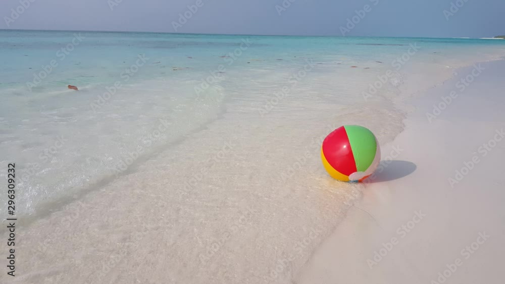 A colorful beach ball rolls around in the gentle tidal waves on a pristine tropical beach in Hawaii A colorful beach ball rolls around in the gentle tidal waves on a pristine tropical beach in Hawaii