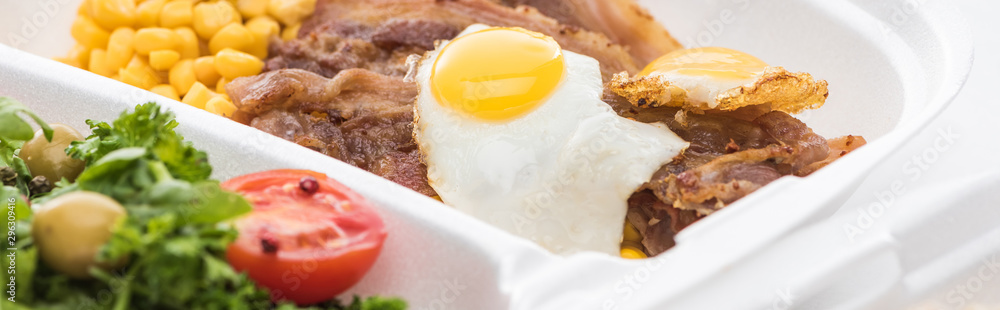 panoramic shot of eco package with corn, meat, fried egg and salad on white background panoramic shot of eco package with corn, meat, fried egg and salad on white background